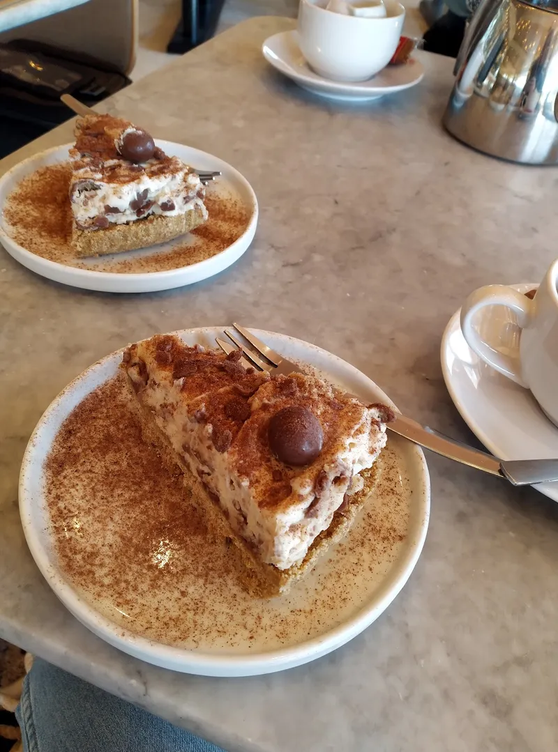 Two slices of cheesecake with coffee on a marble table