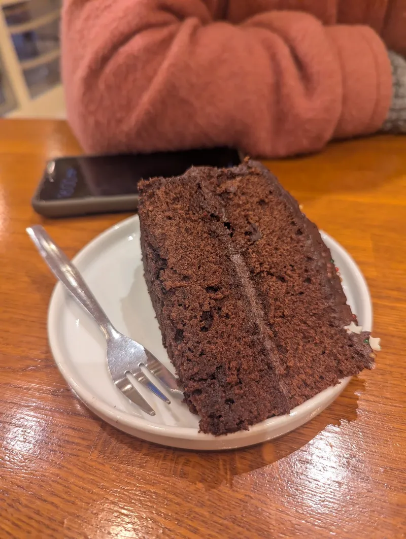 A slice of chocolate layer cake on a wooden table
